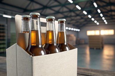 Four-pack carrier holding amber beer bottles in warehouse, ready for bulk distribution