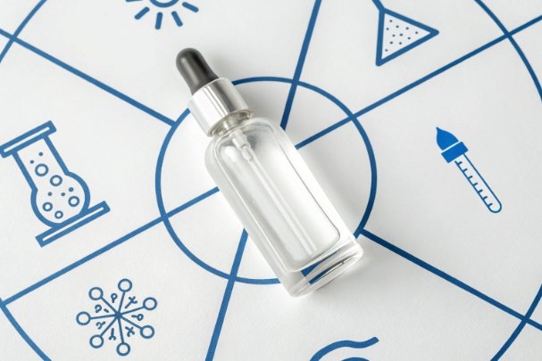 Clear glass dropper bottle on laboratory icons background for cosmetic serum packaging