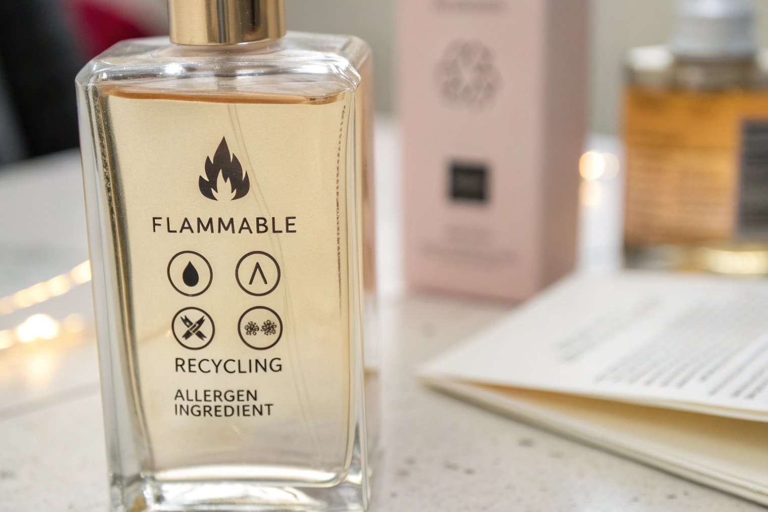 Close-up of a glass perfume bottle labeled with a flame icon, ‘FLAMMABLE’, recycling symbol, and ‘ALLERGEN INGREDIENT’ warnings
