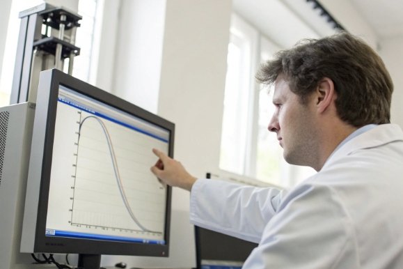 Engineer reviewing thermal curve data on monitor for glass bottle quality control analysis