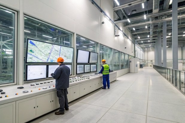Modern glass factory control room with operators monitoring production screens and panels