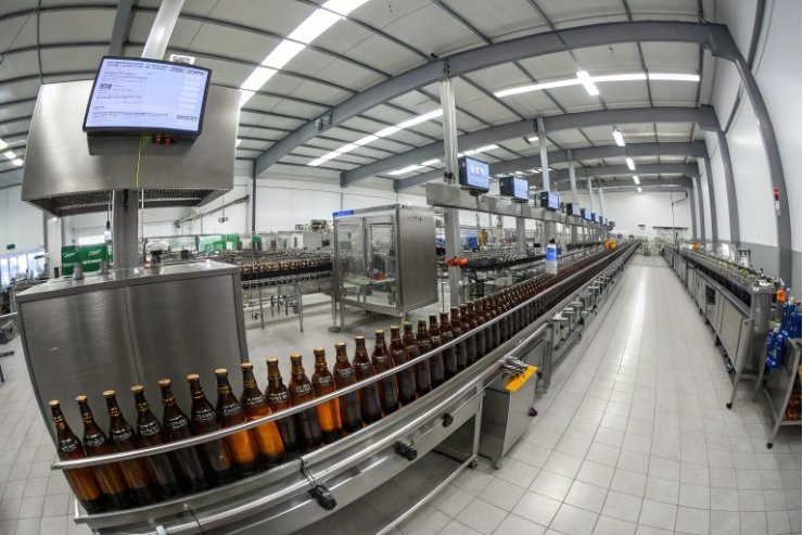 Automated production line with amber glass beer bottles in modern bottling factory