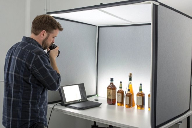 Photographer shooting spirits bottles in lightbox for e-commerce product photography
