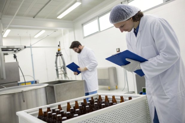 Bottle QC inspection Quality inspectors checking brown glass bottles in cleanroom for packaging compliance