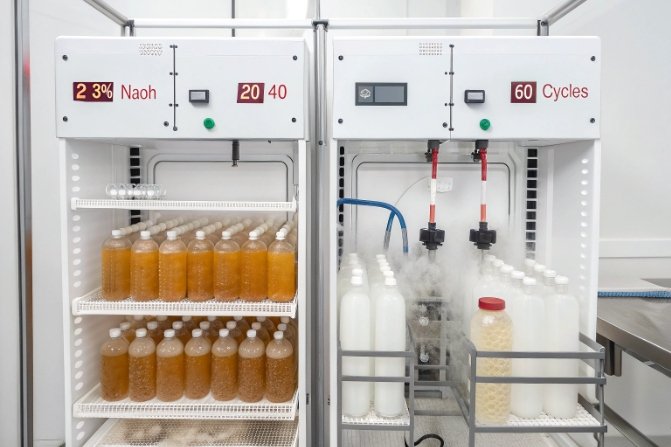 Laboratory NaOH cycle test chambers holding bottles for chemical durability evaluation.