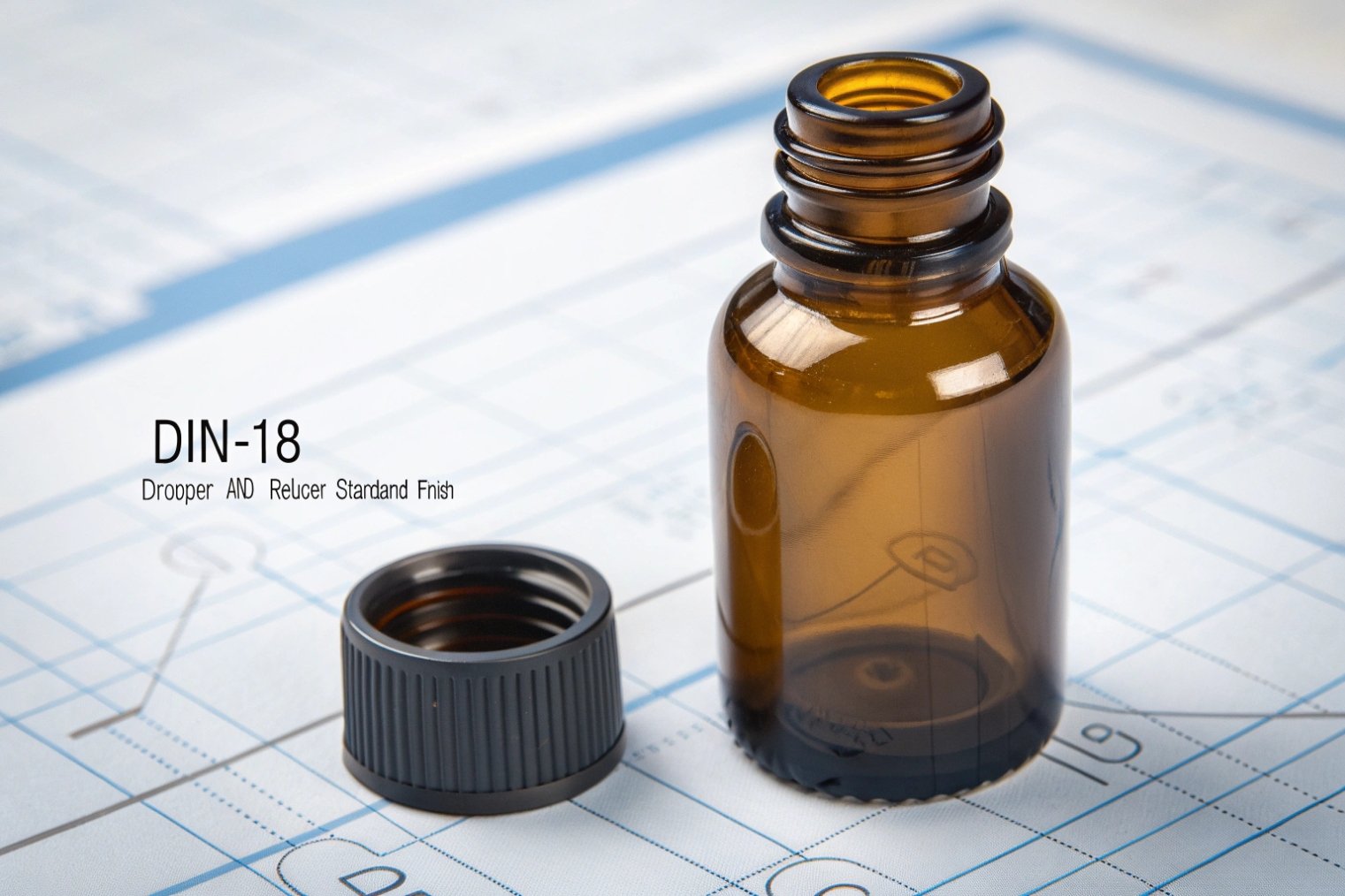 single DIN-18 amber dropper bottle and cap sitting on technical drawings