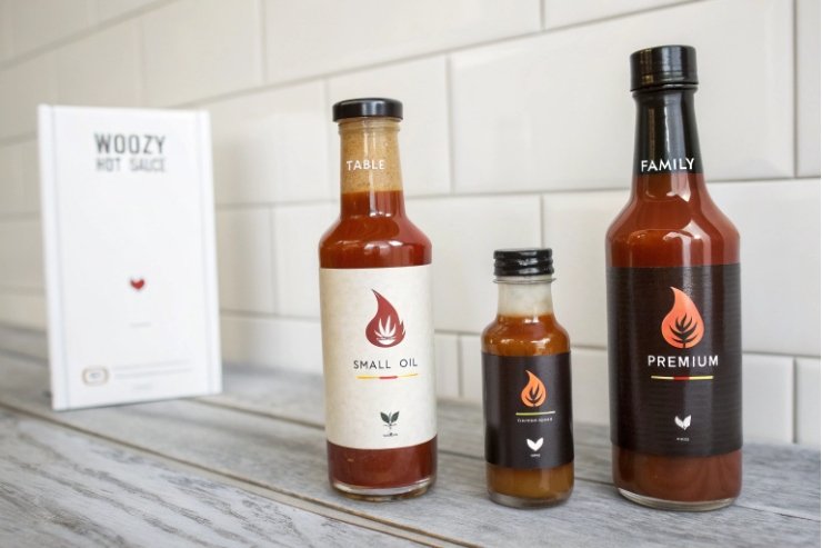 Three hot sauce glass bottles in small, table, and family sizes with branded labels.