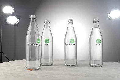 Reusable clear glass water bottles lineup with eco labels on studio table