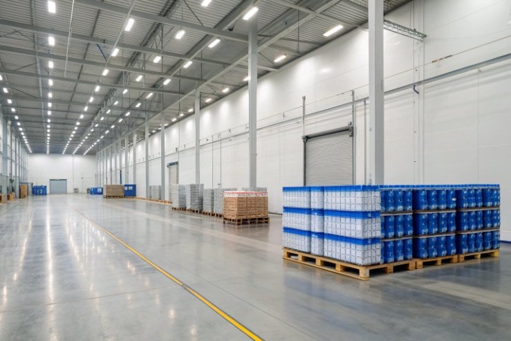 Clean warehouse with pallets of shrink-wrapped glass bottles ready for wholesale shipping