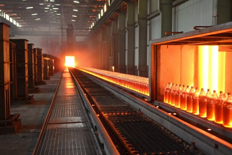 Annealing lehr tunnel with glowing bottles cooling on industrial conveyor line