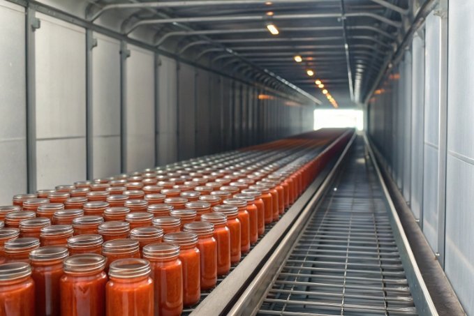 industrial conveyor line of sealed glass jars filled with tomato sauce