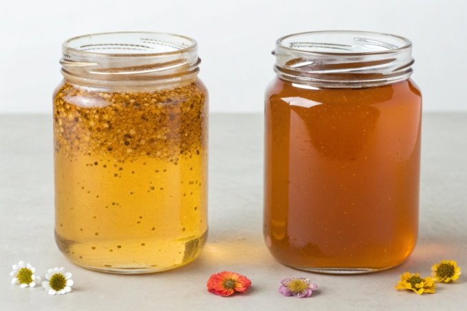 comparison of crystallized honey and clear honey in glass jars with flowers
