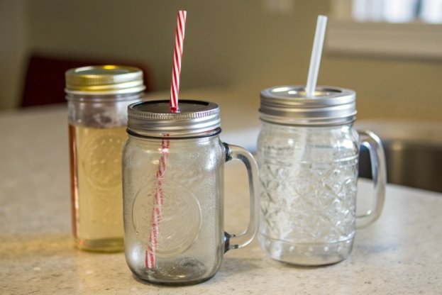 mason jar drinking glasses with metal lids and straws on kitchen counter