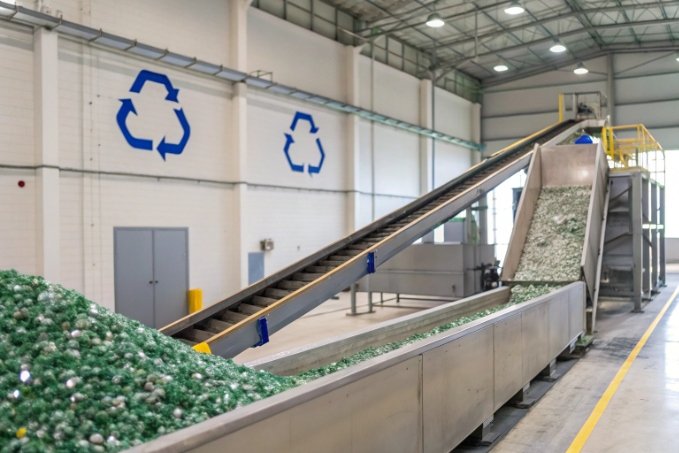 industrial glass recycling facility with conveyors moving crushed bottles for reprocessing