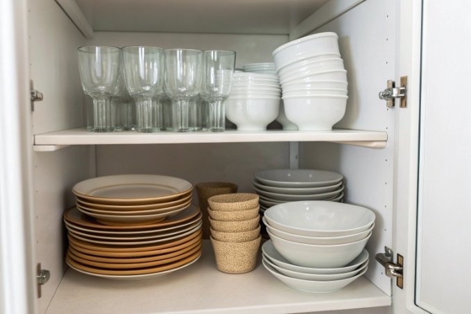 Neatly arranged glassware and plates in a kitchen cupboard