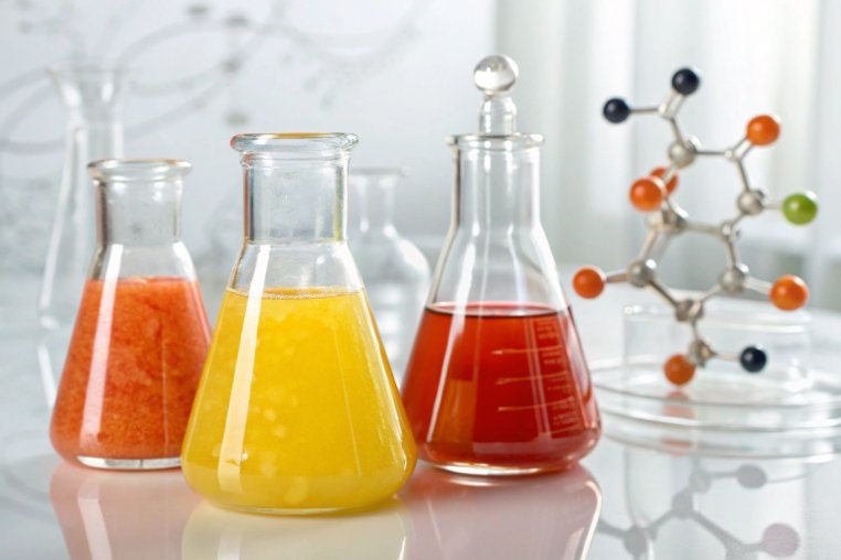 laboratory glass flasks filled with colorful chemical solutions and molecule model