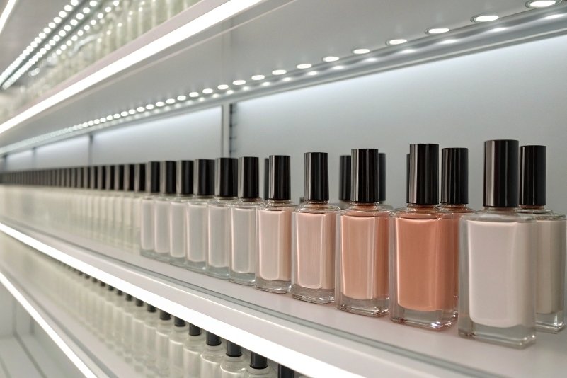 rows of nail polish glass bottles displayed on illuminated retail shelves