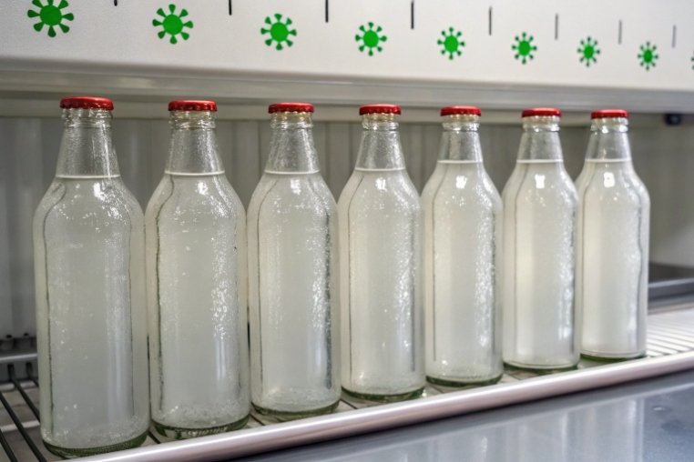 Row of sealed glass bottles undergoing cold temperature resistance test in lab chamber