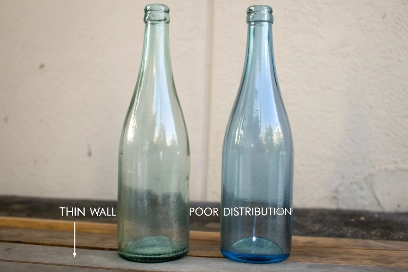 Two tall glass bottles showing thin wall and poor thickness distribution