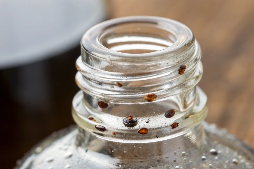 Closeup of glass bottle neck with brown contamination spots and residue