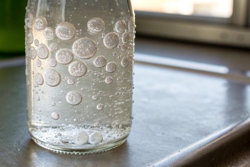 Clear bottle showing large round gas bubbles inside liquid or glass