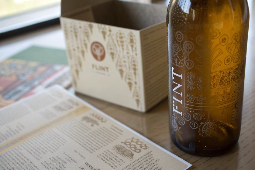 Amber printed glass beer bottle with branded packaging and menu on table
