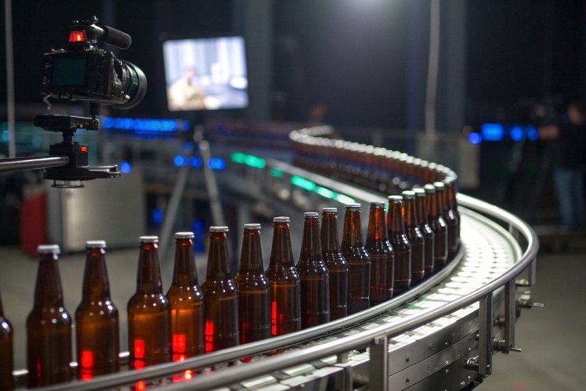 amber beer bottles moving along curved conveyor in automated factory