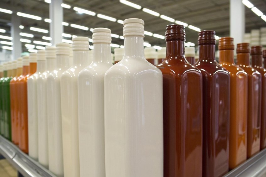 rows of coated glass bottles in white and brown colors on production rack