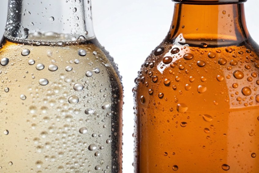 close up of cold clear and amber beer bottles with condensation droplets