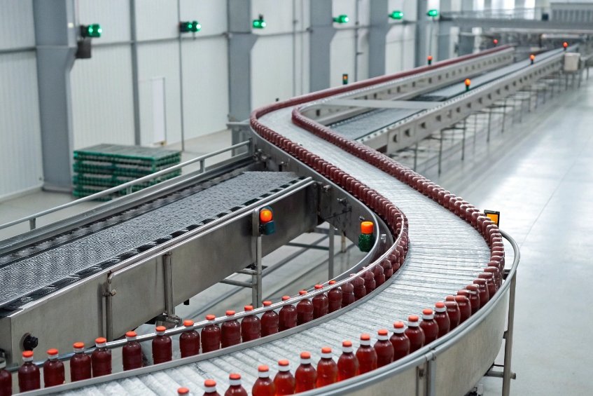curved conveyor of red beverage bottles in modern bottling plant