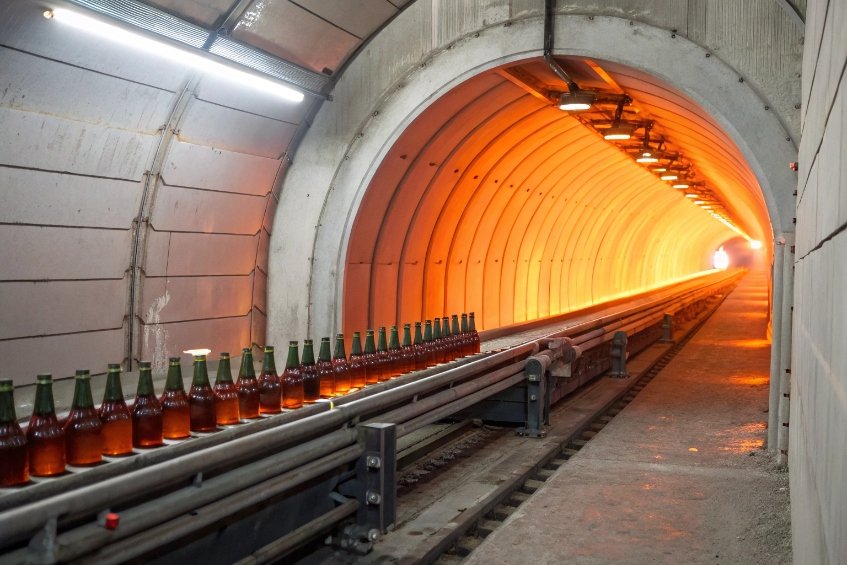 glass beer bottles entering hot annealing tunnel with glowing orange light