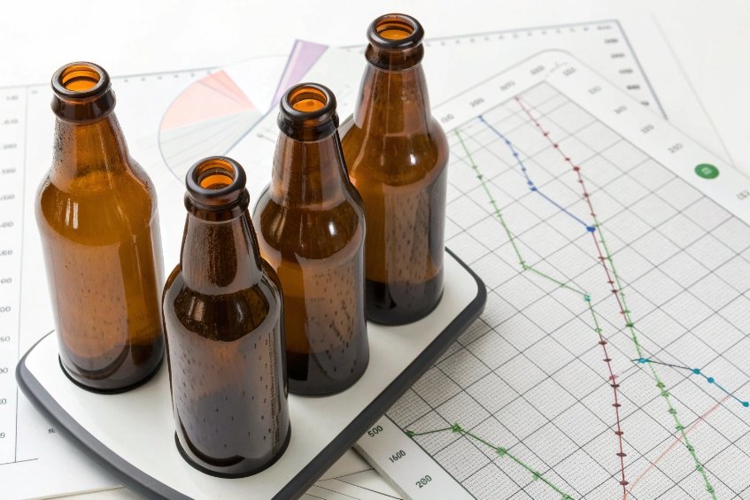 four empty amber beer bottles on scale with quality control charts background