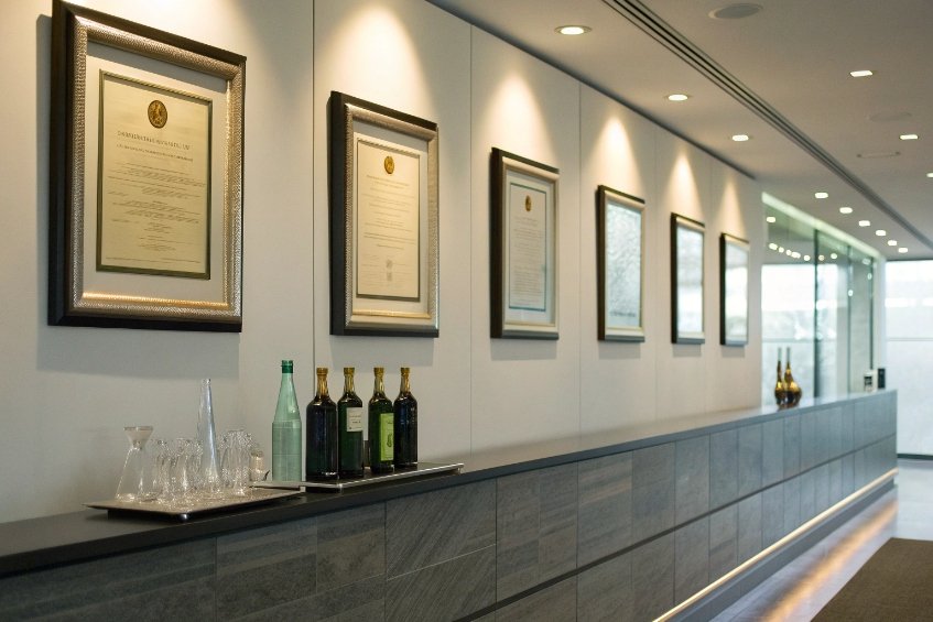 corporate hallway with framed certificates and glass bottles displayed on long reception counter