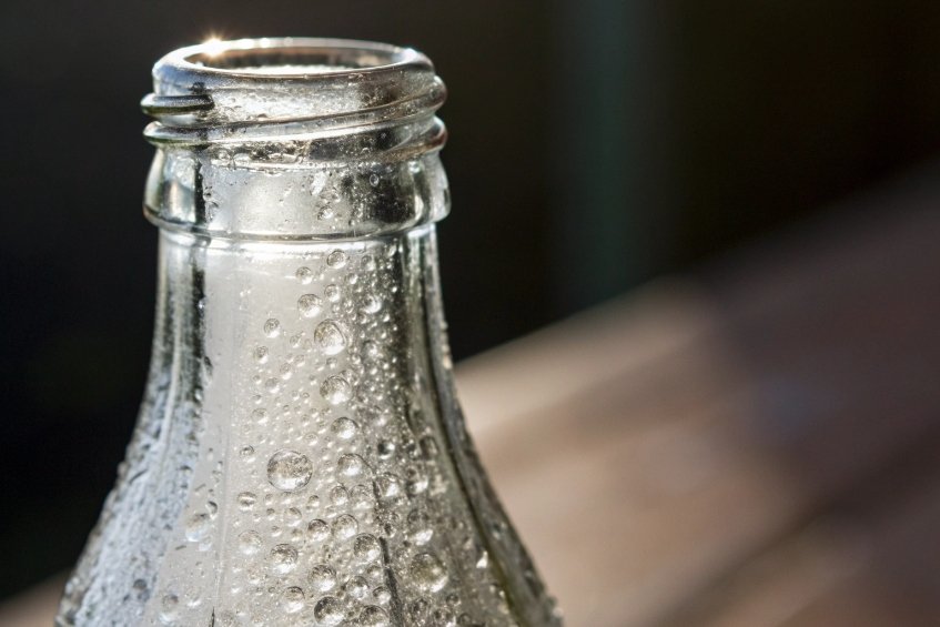 close up of neck of clear glass bottle covered in condensation droplets