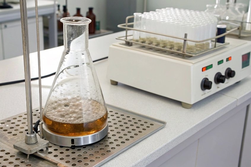 Erlenmeyer flask with heated brown liquid on laboratory hot plate for testing