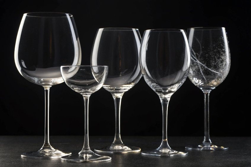 Set of five empty wine glasses on black background showing different bowl shapes