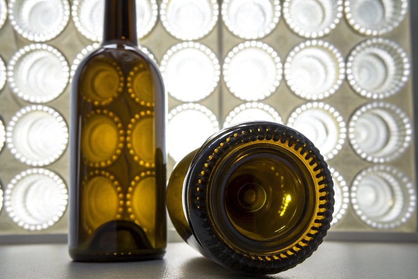 Amber glass wine bottles with detailed punt and base pattern against illuminated inspection panel