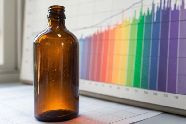 Amber Bottle Analytics Amber glass medicine bottle in front of colorful data chart on screen