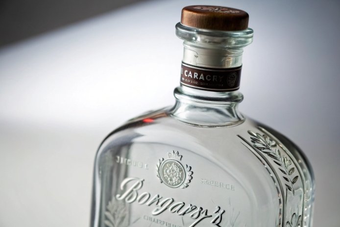 Embossed clear glass liquor bottle close-up with wooden cap and vintage label